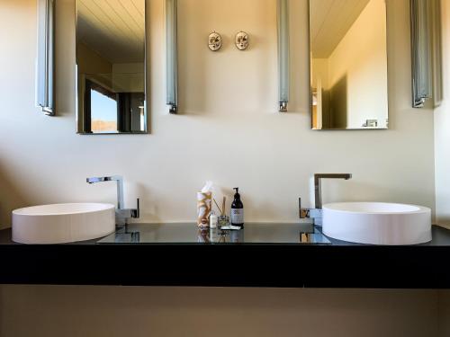 twee wastafels in een badkamer met twee spiegels bij Bannockburn House in Cromwell