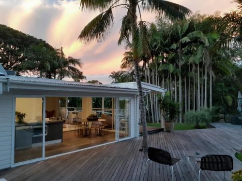 a house with a wooden deck with palm trees at Byron Springs in Byron Bay