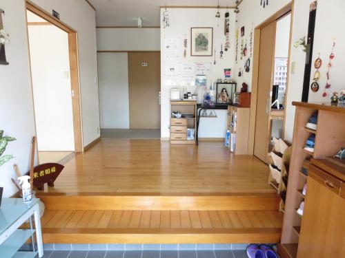 a living room with a wooden floor and a kitchen at Guesthouse Suzukaze in Shibushi