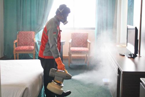 a man standing in a hotel room making a bed at Tunjungan Hotel in Surabaya