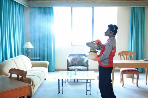 a woman standing in a living room holding a pot at Tunjungan Hotel in Surabaya