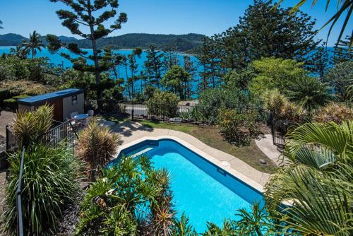 a swimming pool in a garden with a view of the water at Cooinda Gardens on Hamilton Island by HIHA in Hamilton Island