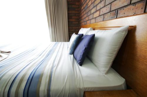 a bed with two blue pillows on it at Golden Palms Motel in Geelong