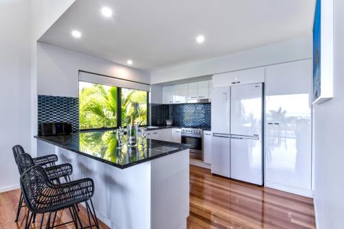 a kitchen with white cabinets and a black counter top at Pinnacle Apartments on Hamilton Island by HIHA in Hamilton Island