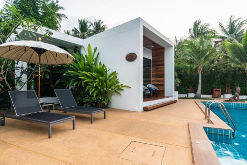 a villa with a swimming pool and two chairs and an umbrella at Zee Luxury Boutique Hotel in Hinkong