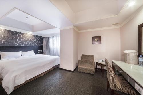 Habitación de hotel con cama, escritorio y silla en 華麗大飯店Ferrary Hotel en Taipéi
