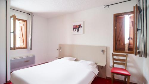 a bedroom with a white bed and a red chair at Vacancéole - Les Chalets de l'Isard in Les Angles