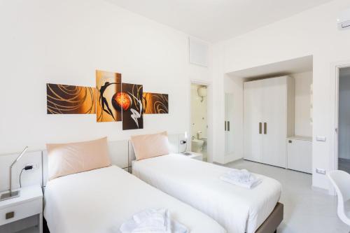 two beds in a room with white walls at Nùe Rooms in Cagliari