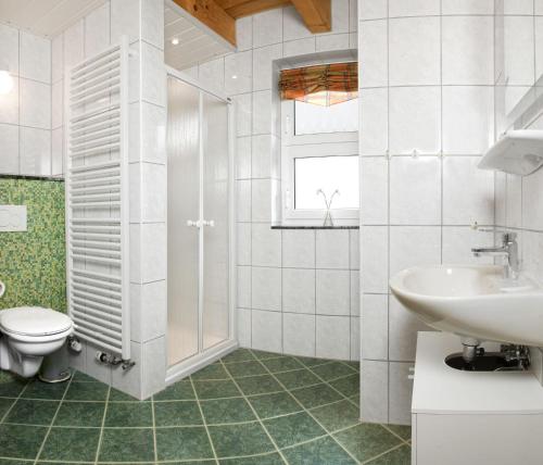 a white bathroom with a toilet and a sink at Haus Gestrandet in Kaltenhof