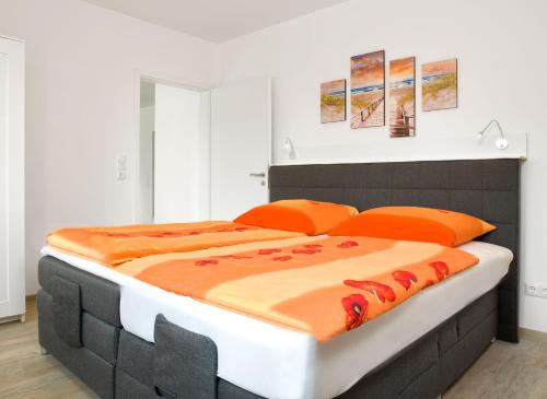 1 dormitorio con 1 cama grande con almohadas de color naranja en Am Krabbenweg Whg.2 im Haus Am Krabbenweg, en Poel