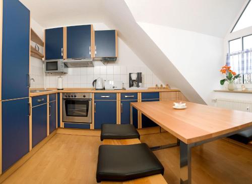 een keuken met blauwe kasten en een houten tafel bij Appartements Am Reiterhof Seepferdchen in Timmendorf