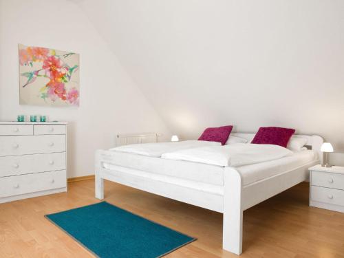 - une chambre avec un lit blanc et une commode dans l'établissement Appartements Am Reiterhof Seepferdchen, à Timmendorfer Strand