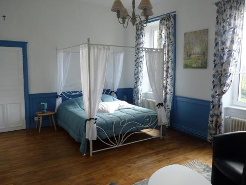 ein Schlafzimmer mit einem Himmelbett mit blauen Wänden und Holzböden in der Unterkunft chateau de Craon in Comblessac