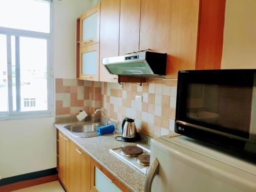 a small kitchen with a sink and a microwave at Quiet studio with king bed, kitchen and balcony in Bangkok