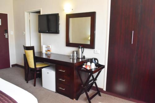 a hotel room with a desk and a mirror at Cresta Bosele Hotel in Selebi-Pikwe