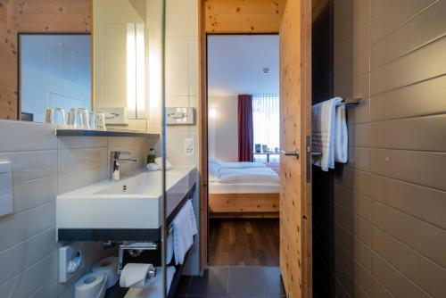 ein Badezimmer mit einem weißen Waschbecken und einem Spiegel in der Unterkunft Arenas Resort Schweizerhof in Sils Maria