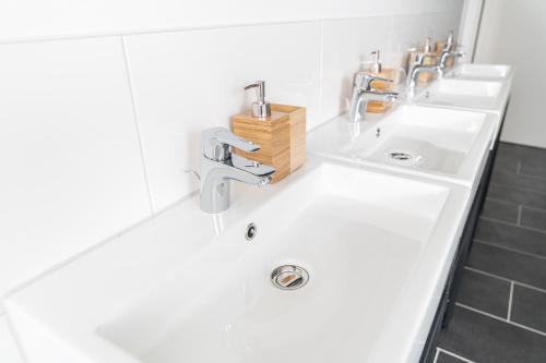 a bathroom with two sinks and two faucets at Hostel Messe Laatzen in Hannover