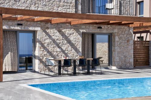 a patio with a table and chairs next to a pool at Anar Villas Rhodes in Koskinou