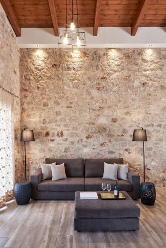 a living room with a couch and a stone wall at Anar Villas Rhodes in Koskinou