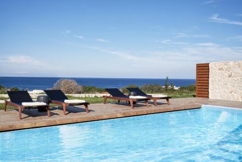 a swimming pool with lounge chairs next to a swimming pool at Anar Villas Rhodes in Koskinou