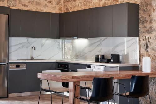 a kitchen with a wooden table and black cabinets at Anar Villas Rhodes in Koskinou