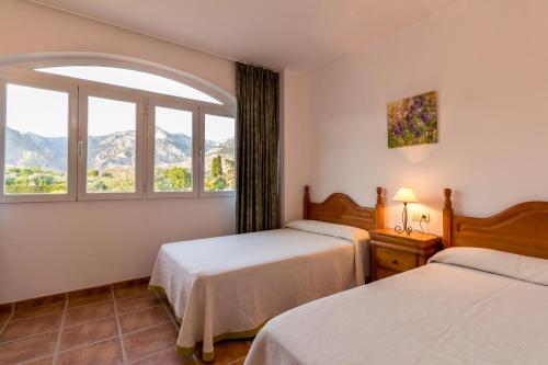 a hotel room with two beds and a window at Venta del alamo in Dúrcal