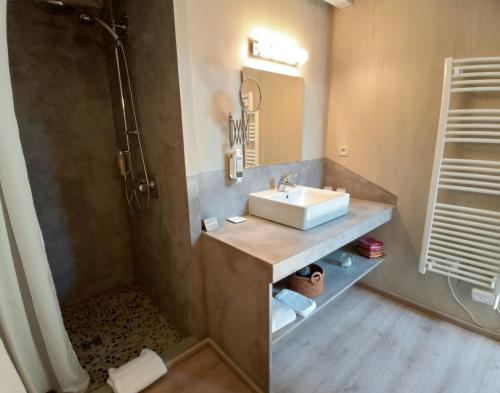 a bathroom with a sink and a shower at Des Lits Sur La Place in Hérépian