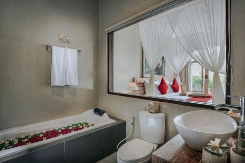 a bathroom with a tub and a toilet and a sink at Kawi Resort Ubud in Tegalalang
