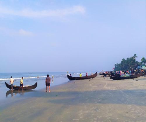 a group of people standing on a beach with boats at Sea Hut Homestay in Cochin