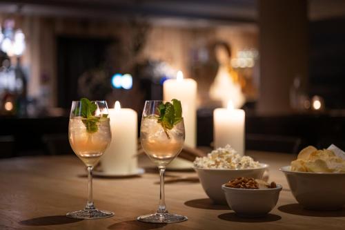 two wine glasses with mint on a table with candles at Hotel Schweizerhof Sils Maria, a Faern Collection Hotel in Sils Maria