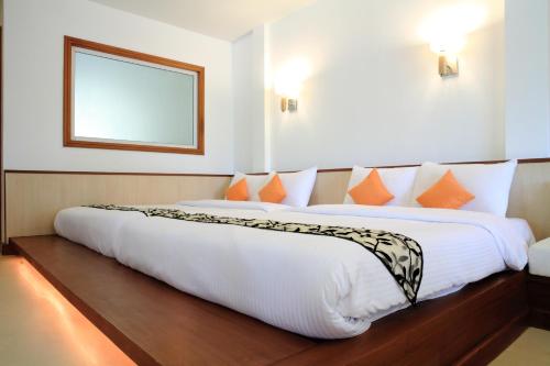 a bedroom with a large white bed with orange pillows at Suan Sai Yok Resort in Sai Yok