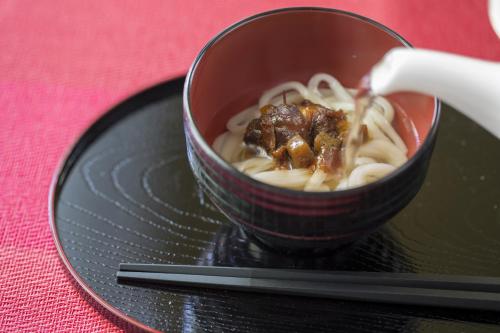 a bowl of food on a black plate with a spoon at Hotel Monterey Kobe in Kobe