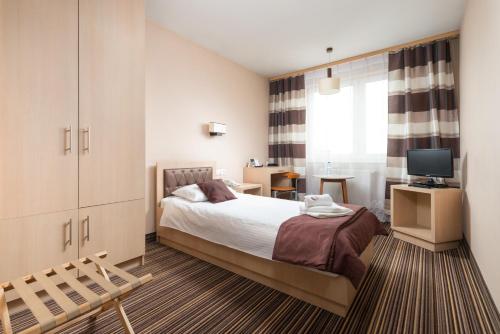 Dormitorio pequeño con cama y TV en Hotel Partner, en Mińsk Mazowiecki