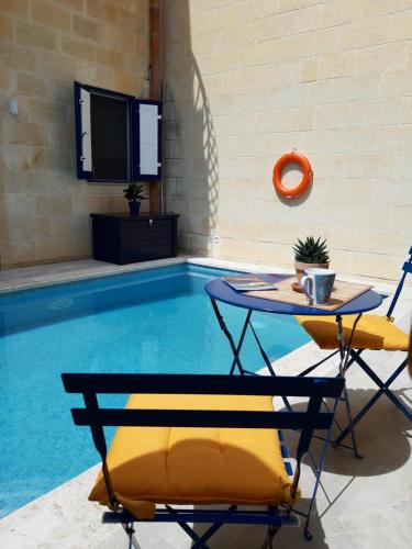 a swimming pool with two chairs and a table at Blueberry House B in Xagħra