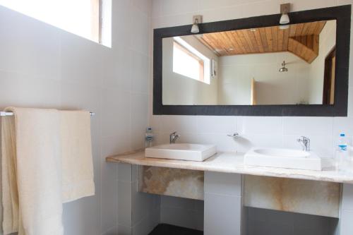 Baño con 2 lavabos y espejo en Utengule Coffee Lodge, en Utengule