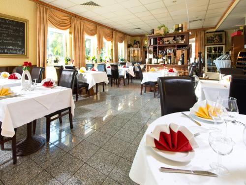 un restaurante con mesas y sillas blancas y una pizarra en ACHAT Hotel Monheim am Rhein, en Monheim