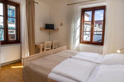 a bedroom with a bed and a table and windows at Hotel Barbakan in Český Krumlov