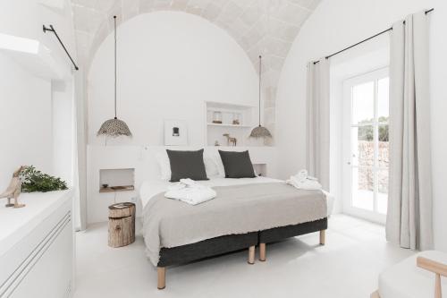 a white bedroom with a bed and a large window at Torre Vella Fontenille Menorca in Son Bou