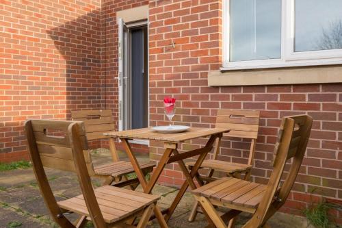 a wooden table with two chairs and a vase of flowers on it at 5 bed house with free parking in quiet location in Wolverhampton