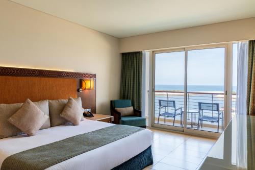 a hotel room with a bed and a balcony at Barceló Mussanah Resort, Sultanate of Oman in Al-Musannah