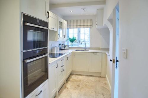 una cocina con armarios blancos y fregadero en Host & Stay - Tithe Cottage en Harrogate