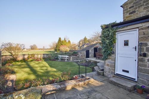 a garden with a white door and a yard at Host & Stay - Tithe Cottage in Harrogate