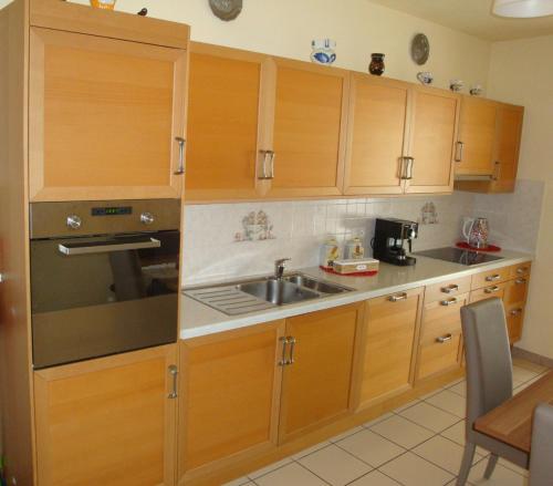 uma cozinha com armários de madeira e um lavatório em Casa Lucini em Campascio
