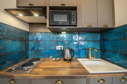 Apartament obejmuje kuchnię ze zlewem i niebieskimi ścianami wyłożonymi kafelkami. w obiekcie Secret Apartments w Kijowie
