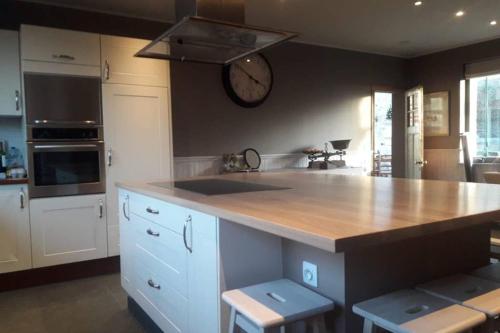 a kitchen with a counter and a clock on the wall at Vakantiehoeve De Klepperij in Houthulst