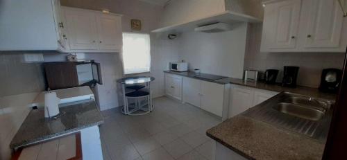 a small kitchen with white cabinets and a sink at Casa S. Félix in Arcos