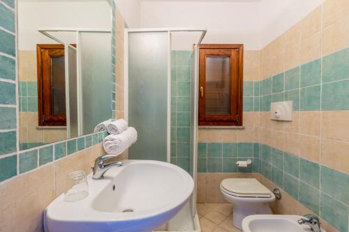 a bathroom with a sink and a toilet and a mirror at Casa Rosa Arancio in Costa Paradiso