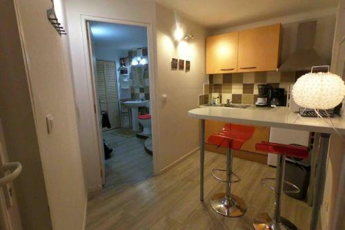 a kitchen with a counter and red stools at Studio rez-de-chaussée, à Lesquin/Lille aéroport in Lesquin