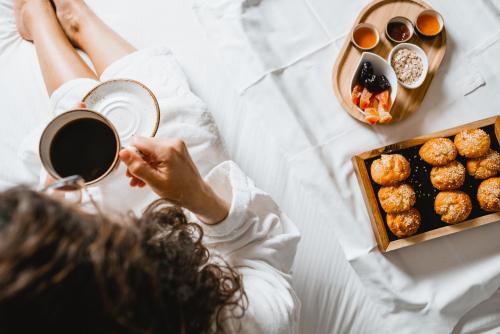 a woman laying on a bed with a tray of food at Marpessa Hotel & Spa in Agrinion
