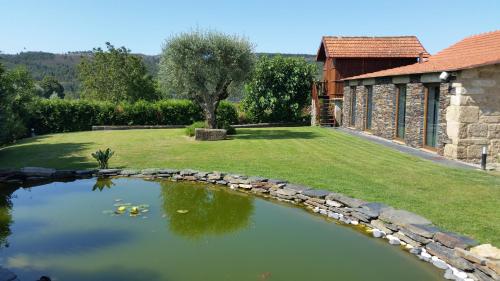 a pond in front of a house with a yard at Casa Valxisto in Penafiel